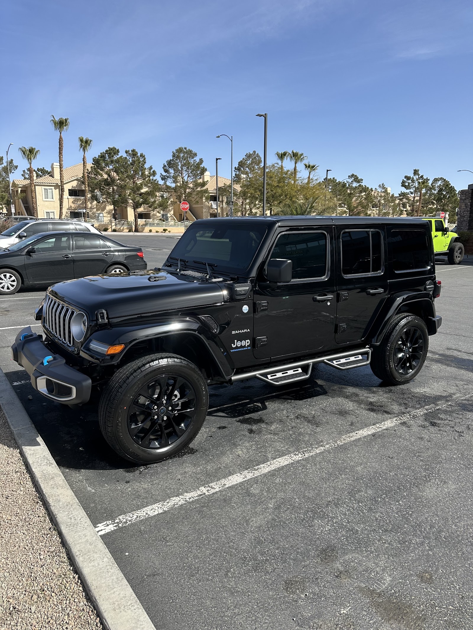 Black Jeep Wrangler Sahara 4xe detailed and glossy in a sunny parking lot